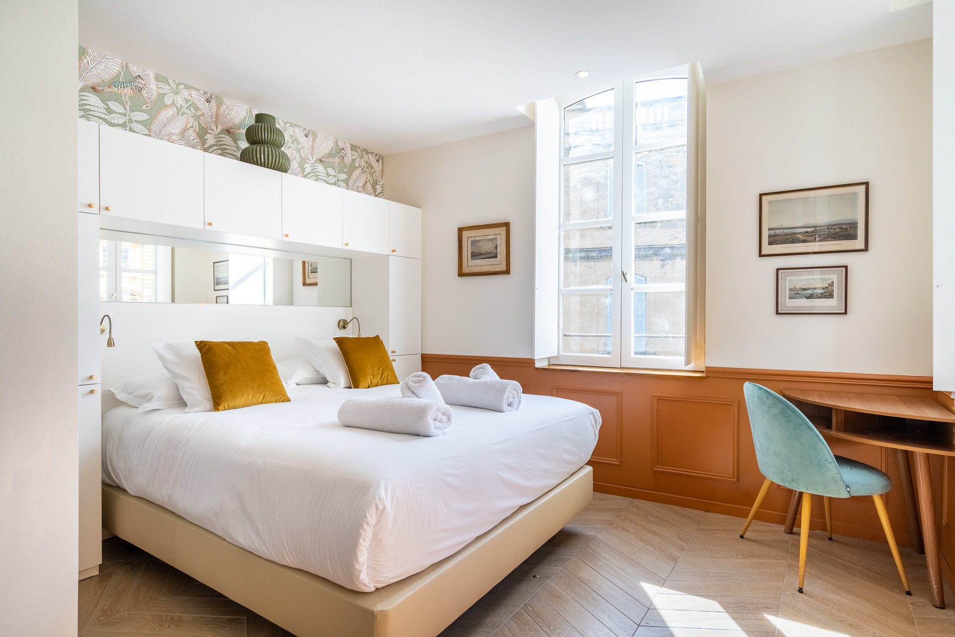 Chambre Deluxe : lit aux coussins moutarde et hautes fenêtres